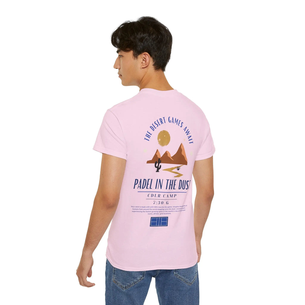 PSF Collective A man wears the Limited Edition - Padel in the Dust Tee by Printify, featuring a desert graphic with mountains, cactus, and sun, plus "The Desert Games Await" and "Padel in the Dust" on the back—ideal for Burning Man padel shirt fans. Designed for the Unwind