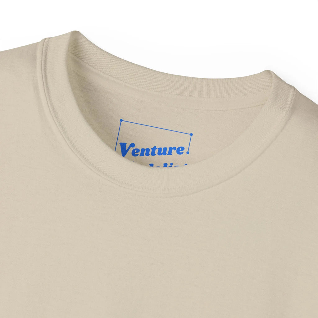 PSF Collective Close-up of the Limited Edition - Padel in the Dust Tee by Printify, a beige crewneck with a blue logo inside the collar. Laid flat on white, it's perfect for fans of unique padel shirts or festival-inspired styles. Designed for the Unwind