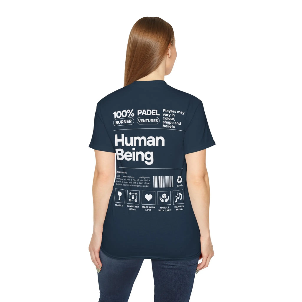 PSF Collective A woman with long brown hair, seen from behind, wears the Printify Limited Edition "Human Being" Tee in navy. The back features bold white text reading “100% Human Being” with icons and phrases styled like a product label. Designed for the Unwind