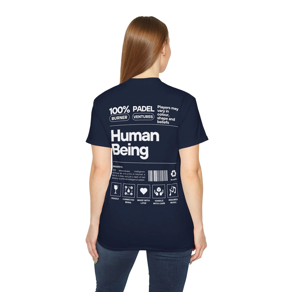PSF Collective A woman with straight light brown hair, seen from behind, wears the Printify Limited Edition "Human Being" Tee in navy blue, featuring white 100% Human Being text and playful mock label graphics. Designed for the Unwind