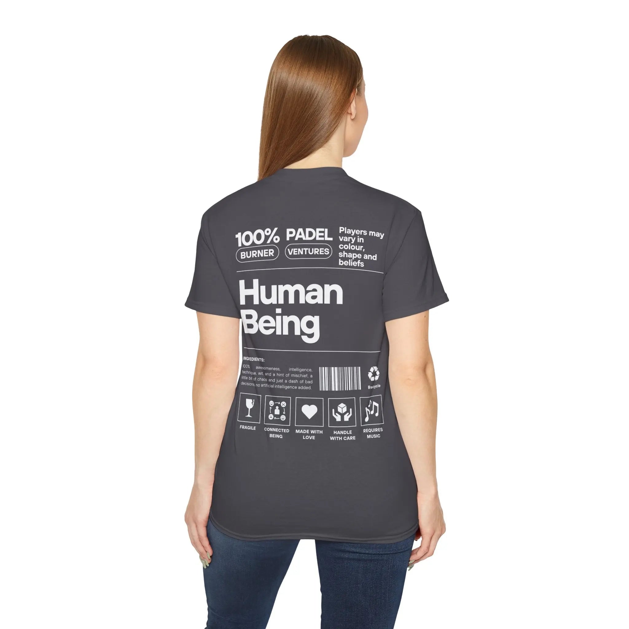 PSF Collective A woman with long brown hair faces away, wearing the Printify Limited Edition "Human Being" Tee in gray, featuring white text and graphics on the back that resemble a product label. Designed for the Unwind
