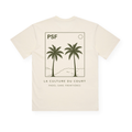 PSF Collective Introducing the Two Palms Box Tee: a cream-colored T-shirt featuring a minimalist line drawing of two palm trees, hills, and a sun enclosed in a rectangle. “PSF” is printed above the artwork, with “LA CULTURE DU COURT” and “PADEL SANS FRONTIÈRES” below. Designed with a relaxed box fit and the graphic centered on the back, this tee delivers an effortlessly vintage coastal look. Designed for the Unwind