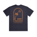 PSF Collective Sun Arch in Orange Box Tee: A navy T-shirt featuring a retro-inspired graphic of a palm tree beneath the sun, framed by an arch. The text “Padel Sans Frontières” is displayed prominently, with “La Culture Du Court” written below in smaller letters. This design captures a relaxed, summery, and sporty vibe. Designed for the Unwind