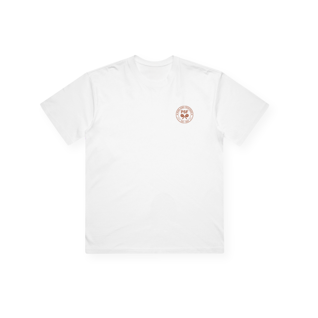 PSF Collective The Sunsmash Box Tee is displayed lying flat against a completely white background. This plain white tee features short sleeves and is adorned with a small, circular brown emblem on the left chest area that displays “PSF” alongside a simple graphic. No other designs or markings are visible on the shirt. Designed for the Unwind