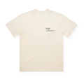 PSF Collective The cream-colored Summer Arch in Green Box Tee is shown laid flat. This short-sleeve t-shirt features small, dark green cursive text reading “Padel Juniors” on the left chest. With its vintage sport style, classic crew neckline, and minimalistic design free from additional graphics or patterns, this tee offers a timeless look. Designed for the Unwind