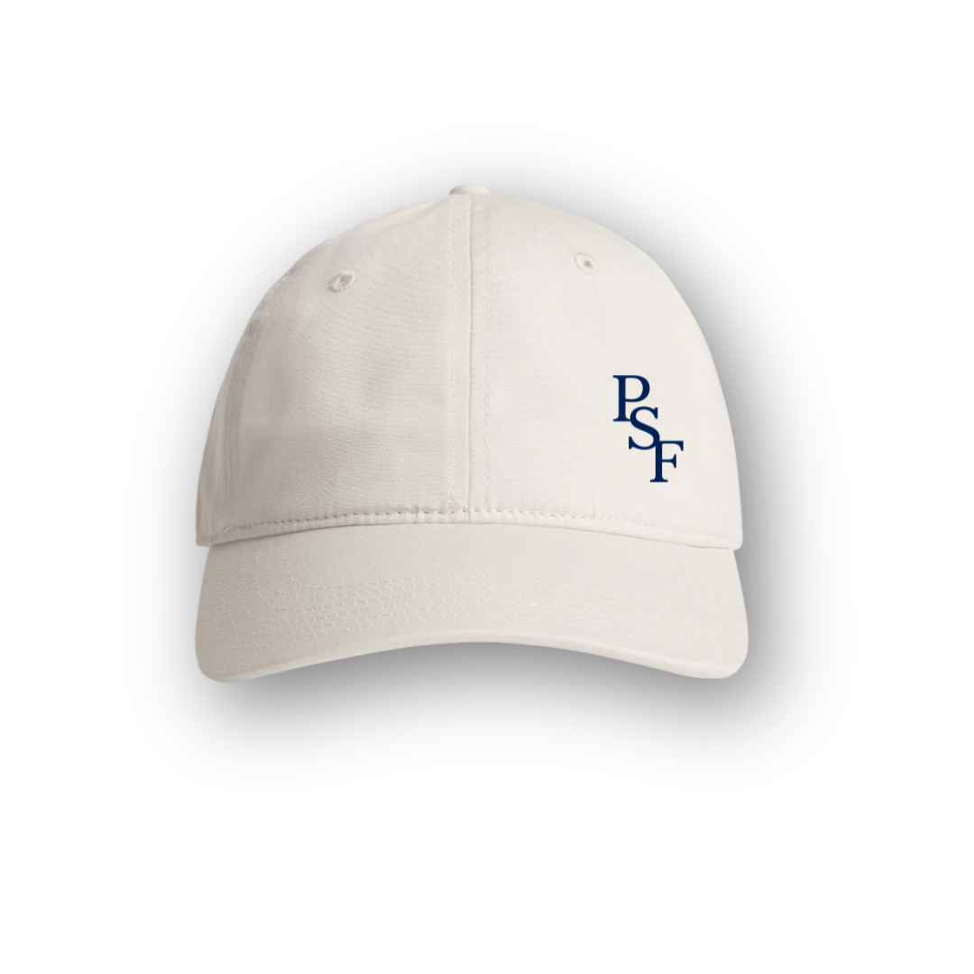 PSF Collective The Heritage Cap in Off White features a small dark blue PSF logo embroidered on the front left panel. Visible stitching and a curved brim evoke a classic vintage sportswear style. The cap is photographed against a white background with a soft shadow beneath it. Designed for the Unwind