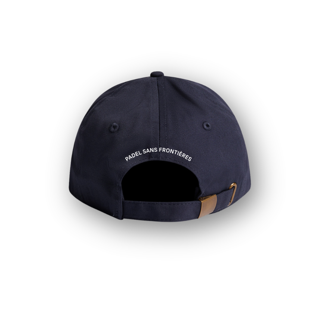 PSF Collective Viewed from the back, The Heritage Cap in Navy features an adjustable strap with a brass buckle and is adorned with white “PADEL SANS FRONTIÈRES” text above the opening. The cap is set against a plain white background with a soft shadow surrounding it. Designed for the Unwind