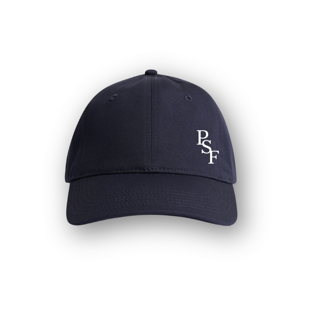 PSF Collective A plain navy Heritage Cap viewed from the front, featuring the white letters PSF embroidered on the right front panel. The background is white with a soft shadow around the cap. Designed for the Unwind